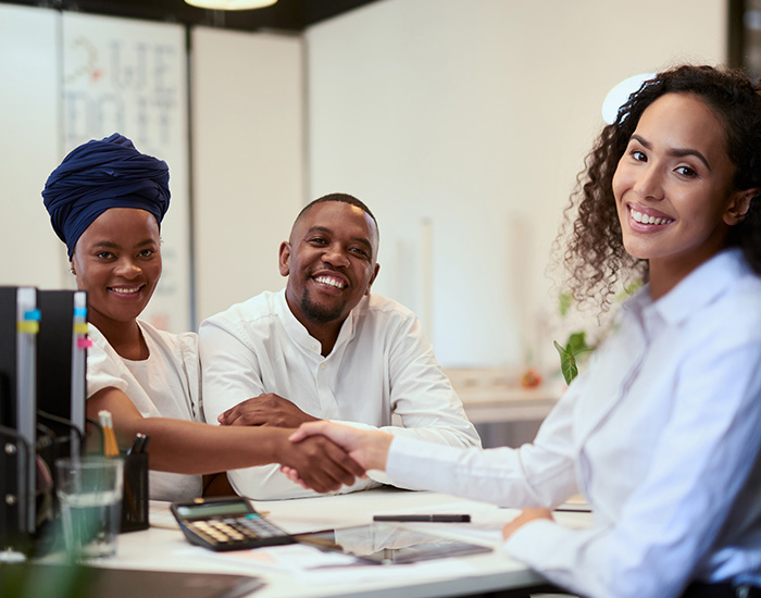 Handshake, agreement and success for married couple meeting with lawyer